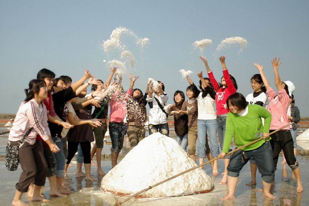 Tourists experiencing the drying, raking, and collecting of salt.